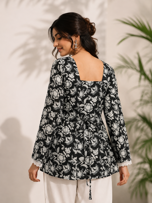 Full-length view of woman styling black and white floral kurti with white trousers