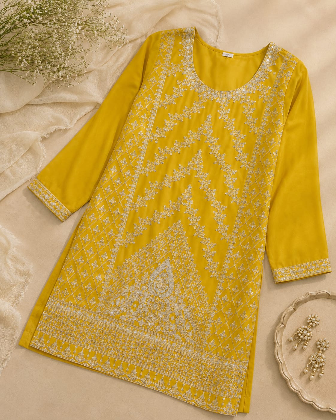 Mustard yellow embroidered kurta with intricate white embroidery and detailed hem