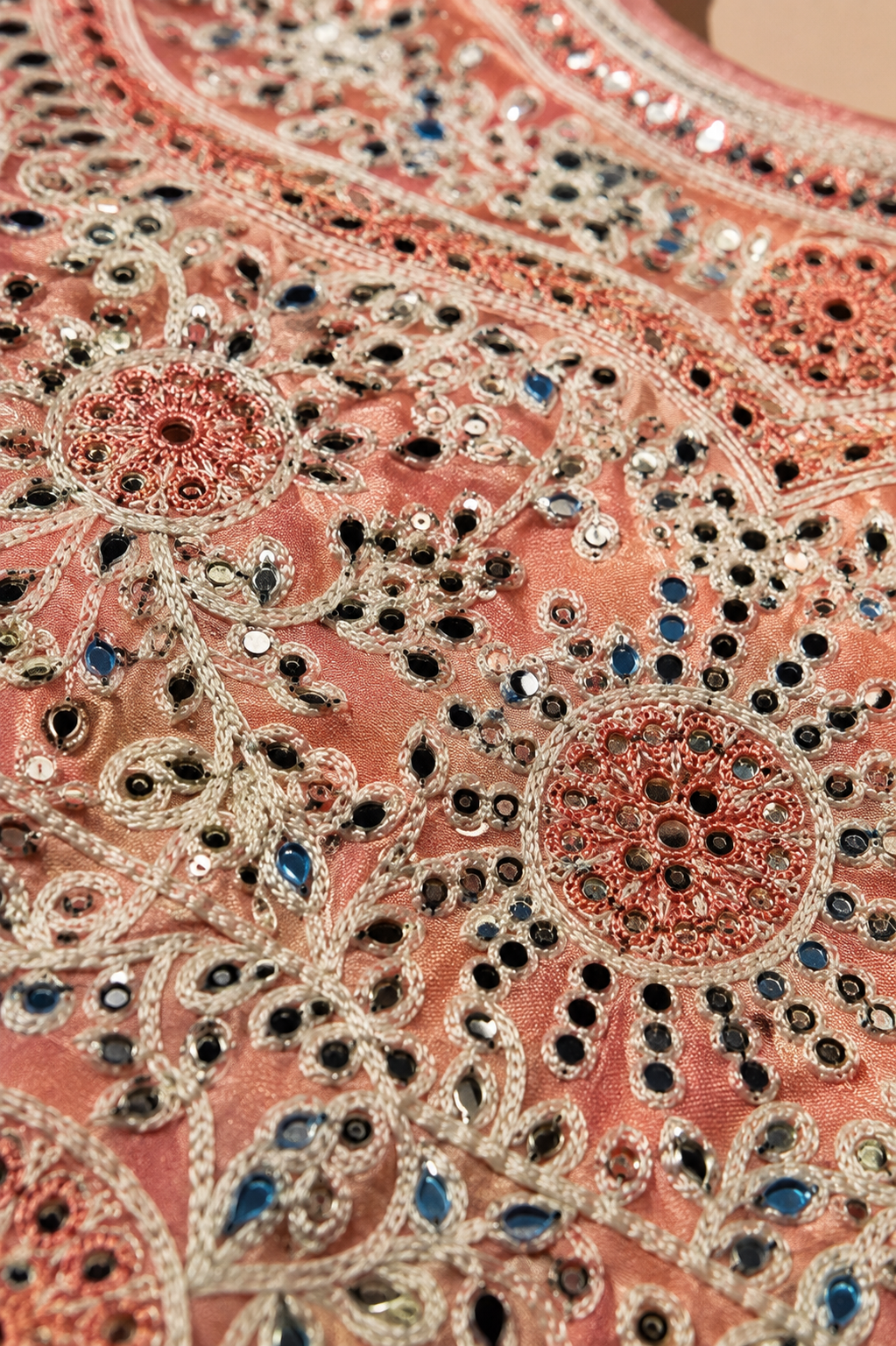 Close-up of intricate floral embroidery, threadwork and embellishments on peach ethnic wear top
